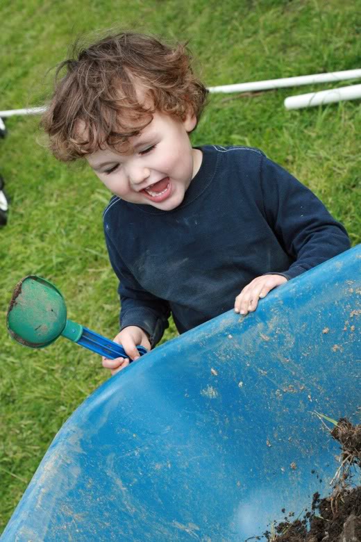 making raised garden beds - boy smiling with shovel