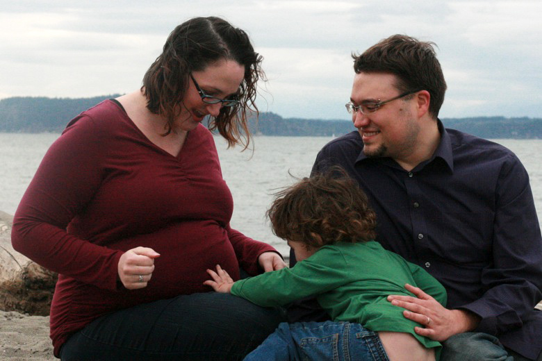 older sibling touching the pregnant baby belly — family maternity photo shoot on the beach