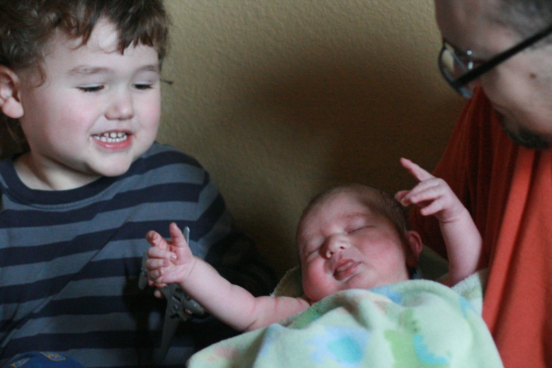 big brother and baby brother meeting — father holding newborn