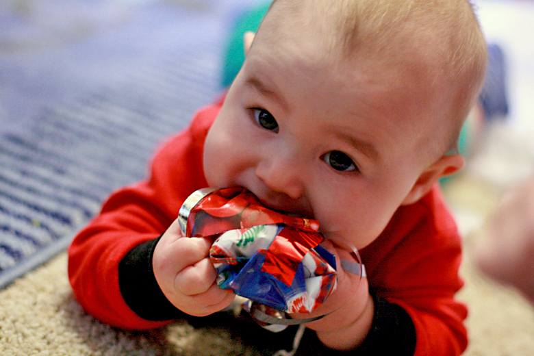 baby eating wrapping paper on Christmas morning