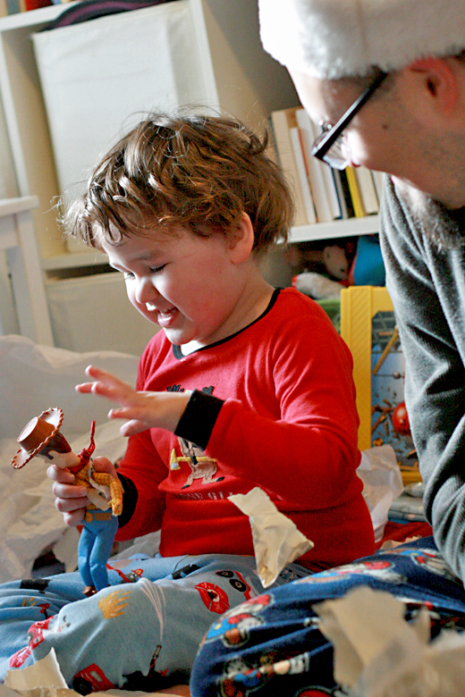 boy opening Woody and presents happily on Christmas morning