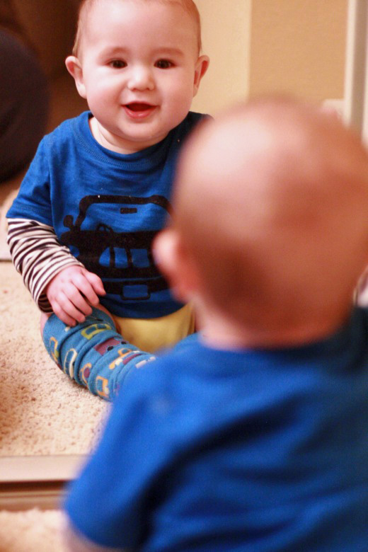 baby waving at himself in the mirror