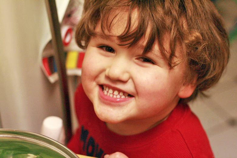 boy smiling in kitchen while cooking