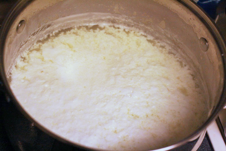 lemon juice in pot of cheese separating into curds and whey - homemade ricotta cheese recipe