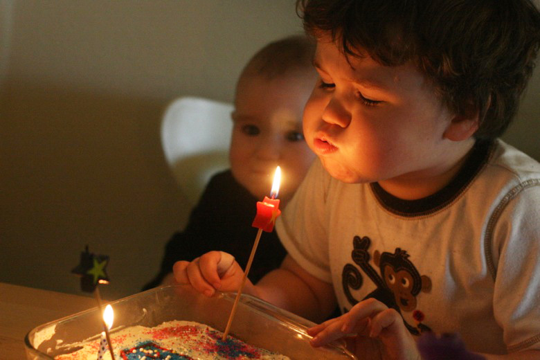 boy blowing out baby's first birthday cake candle