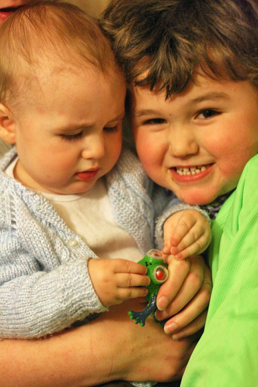 toddler and brother hugging with first birthday present