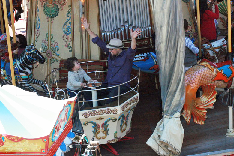 boy and dad enjoying the spinning 2-story carousel &#8212; california road trip travel san francisco