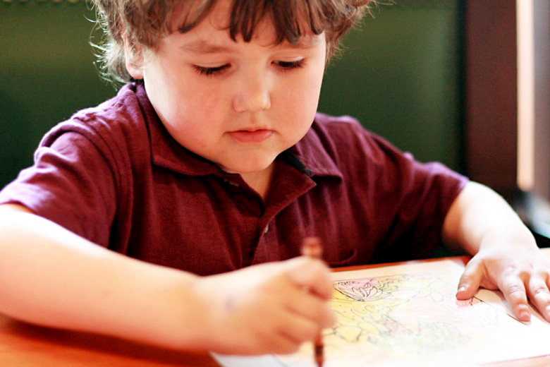 boy coloring at restaurant table