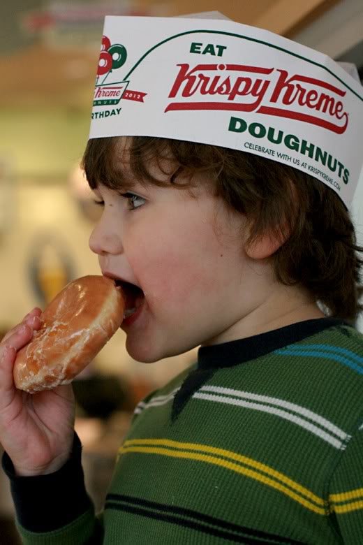 Krispy Kreme donuts boy in paper hat with an original glazed donut