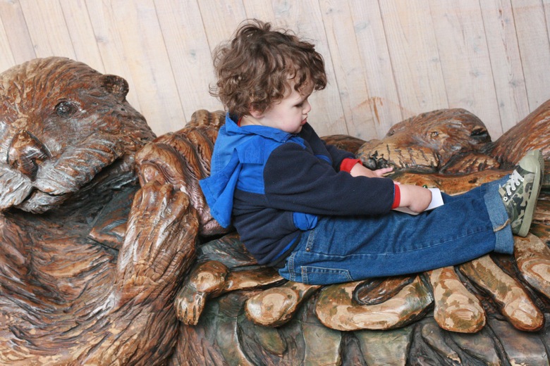 boy sits on sea otter sculpture bench Seattle Aquarium
