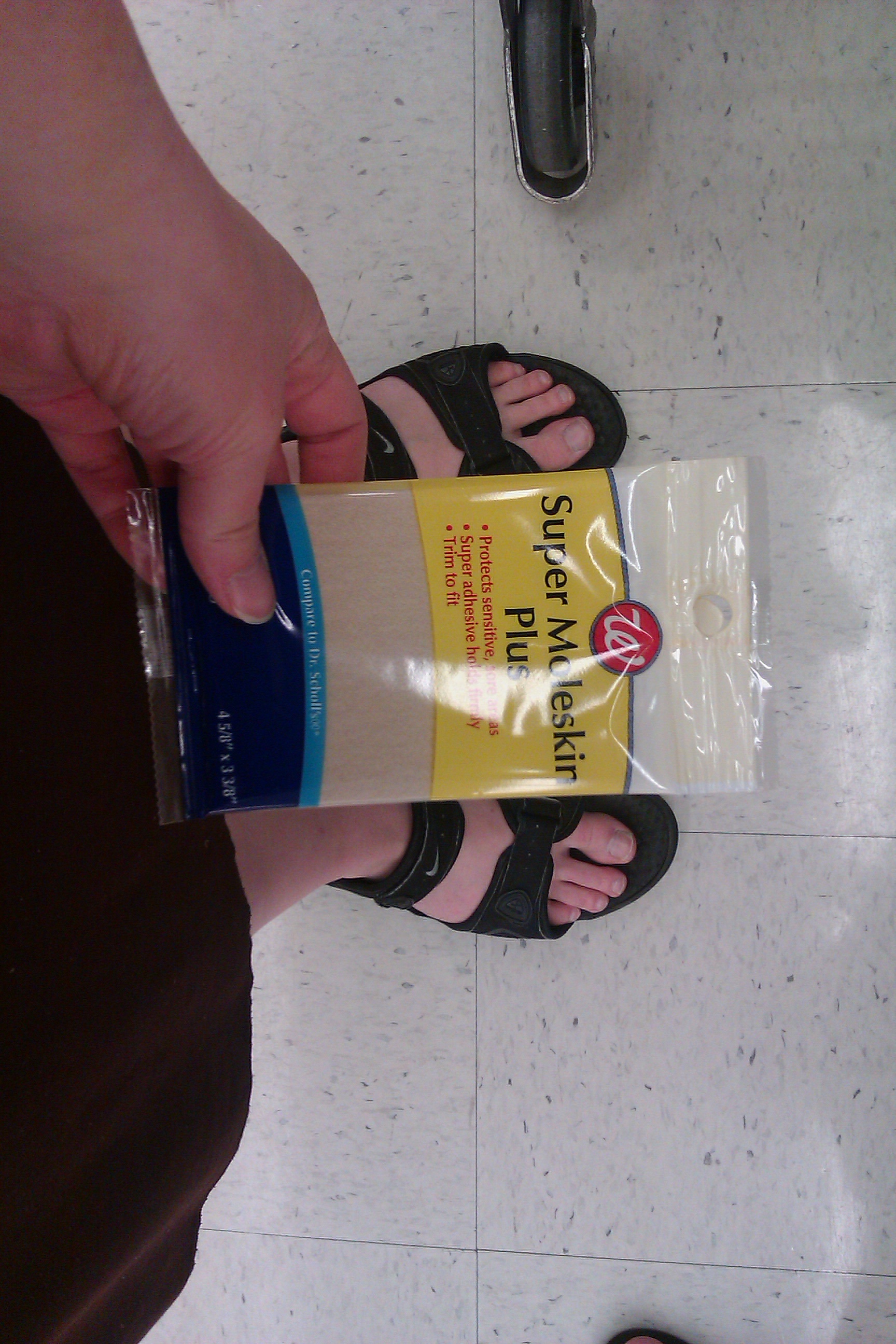 pregnant woman in sandals at Walgreens with Super Moleskin Plus foot cushion bandages