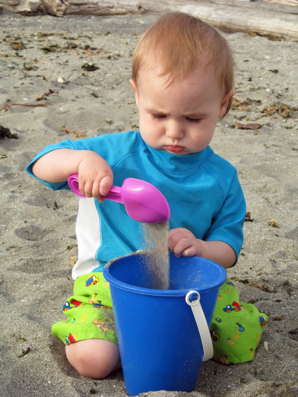 baby playing in sand on beach at family camping