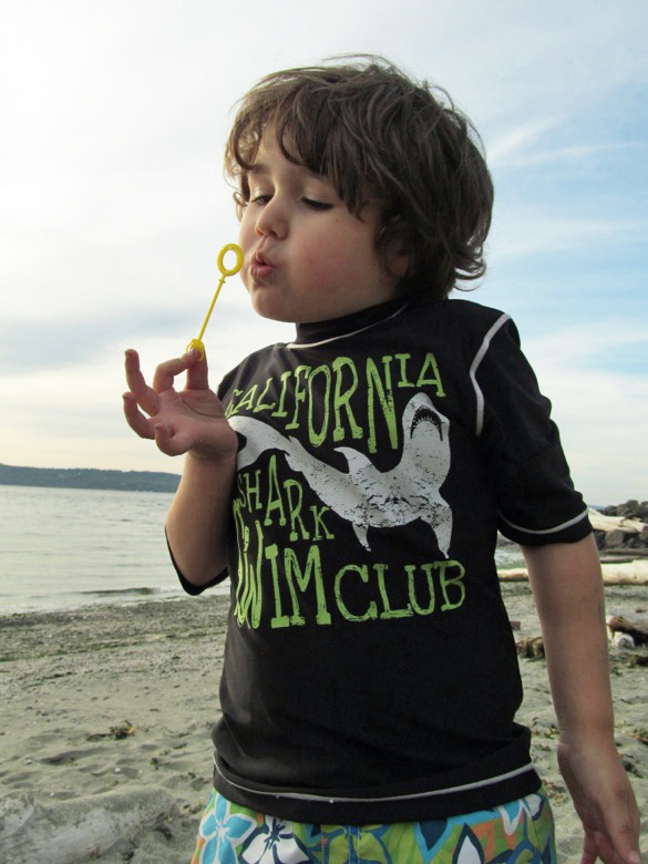 boy blowing bubbles on beach at family camping
