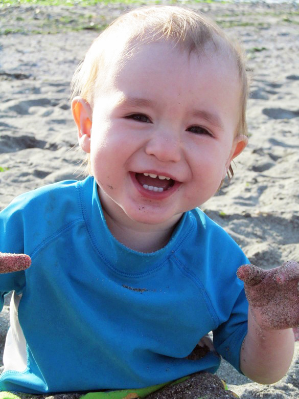 baby smiling on beach in family camping