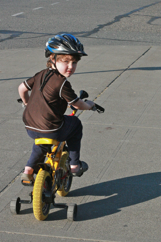 boy riding bike in helmet with training wheels - mikko m5yo biking outdoors