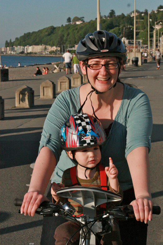 mom and toddler boy in bike helmets on bike with weeride seat on beach - biking outdoors