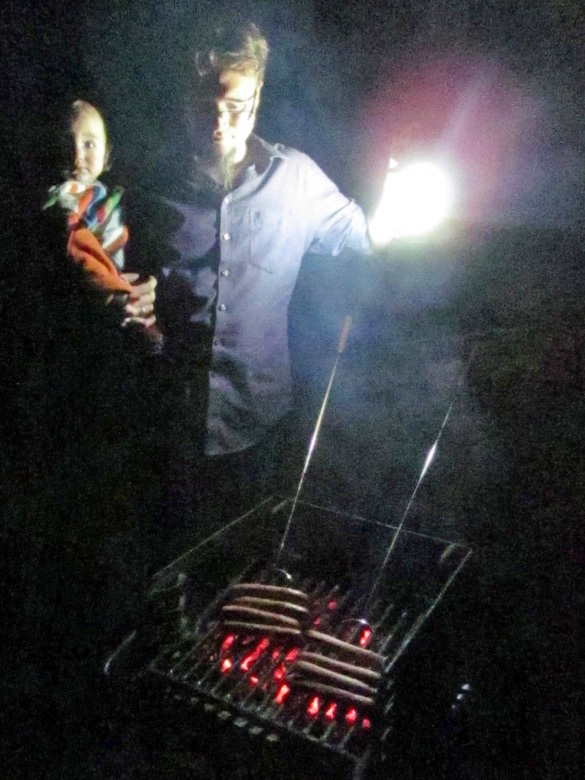 roasting hot dogs and marshmallows on grill in the dark in family camping