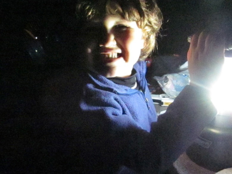 boy smiling in lantern light during dinner in family camping