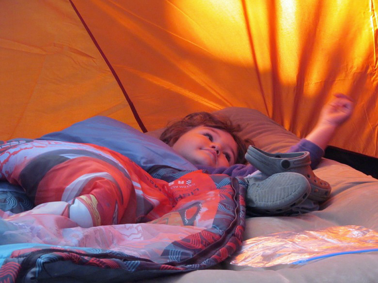 boy lying down in sleeping bag in tent in family camping