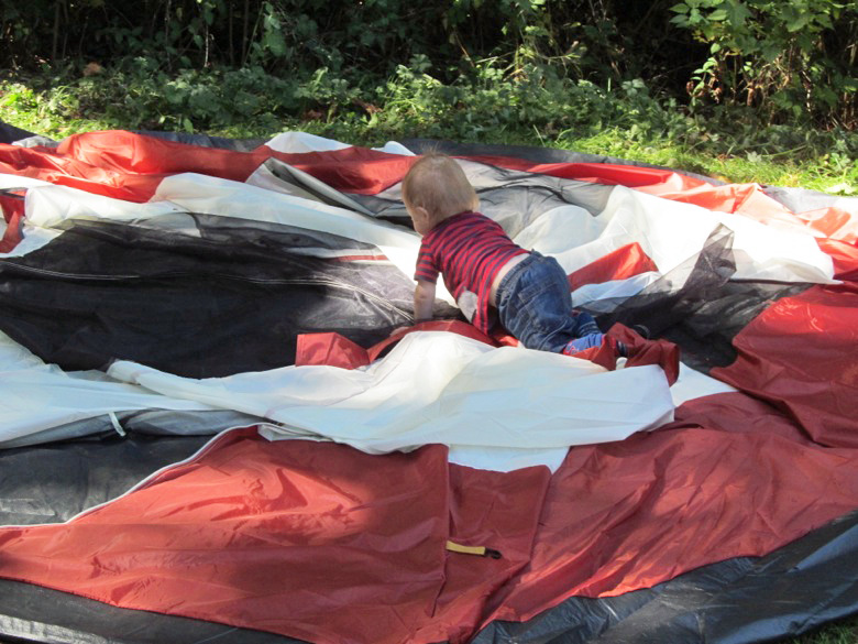 baby crawling on top of collapsed tent in family camping