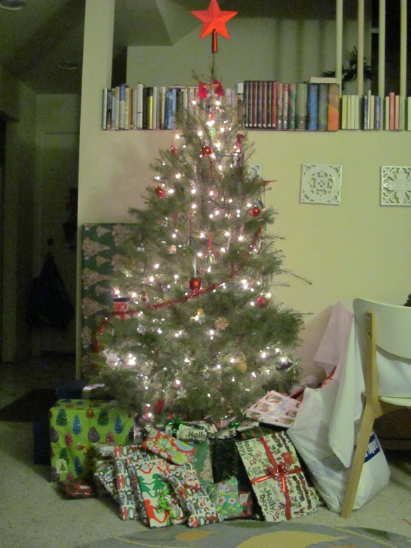decorated and lit tree with presents underneath &mdash;