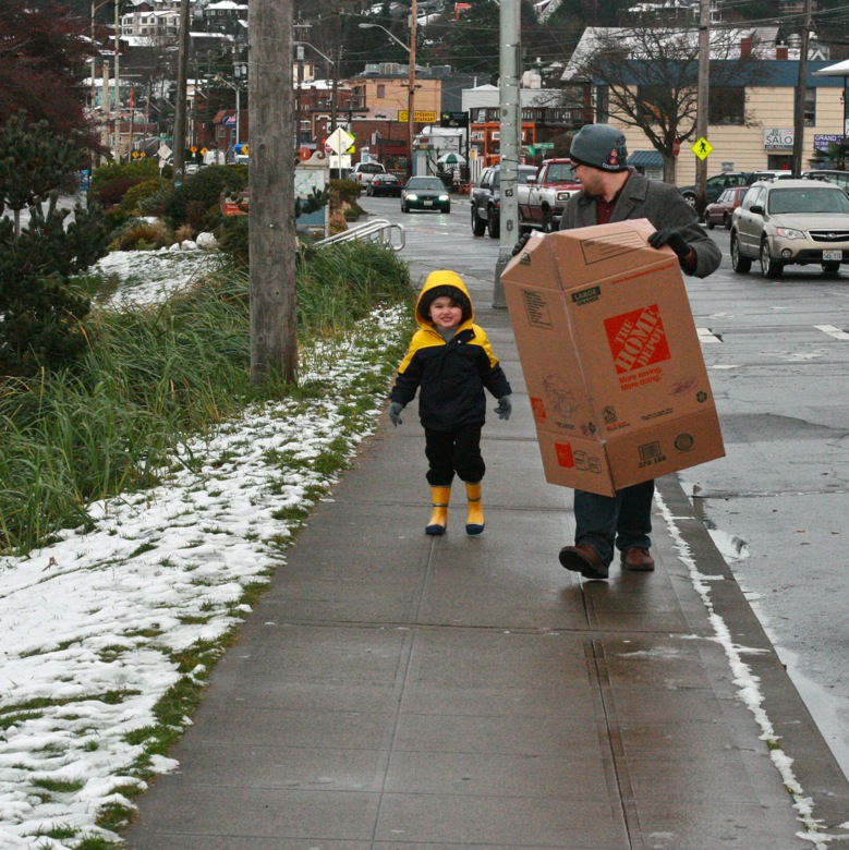 dad and boy carrying cardboard box sled in winter outdoors in Seattle