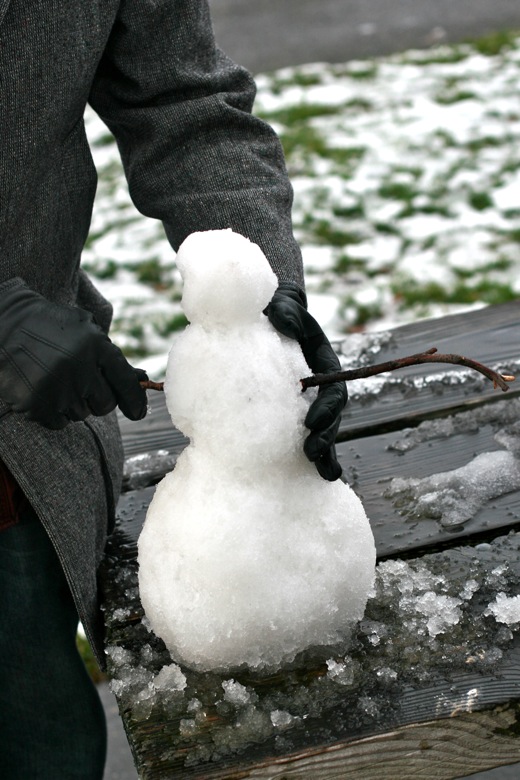 dad building miniature snowman on picnic table in Seattle outdoors in winter