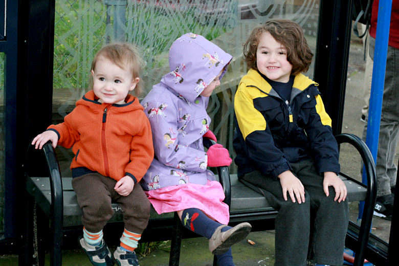 three kids on a bus stop bench - portland trip travel