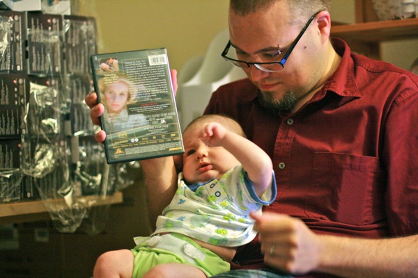 family business —  dad sam holding alrik anb newborn baby while working on dvd