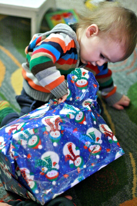 baby peeks inside present while unwrapping &#8212;&nbsp;christmas12 holidays alrik a1yo a18mo
