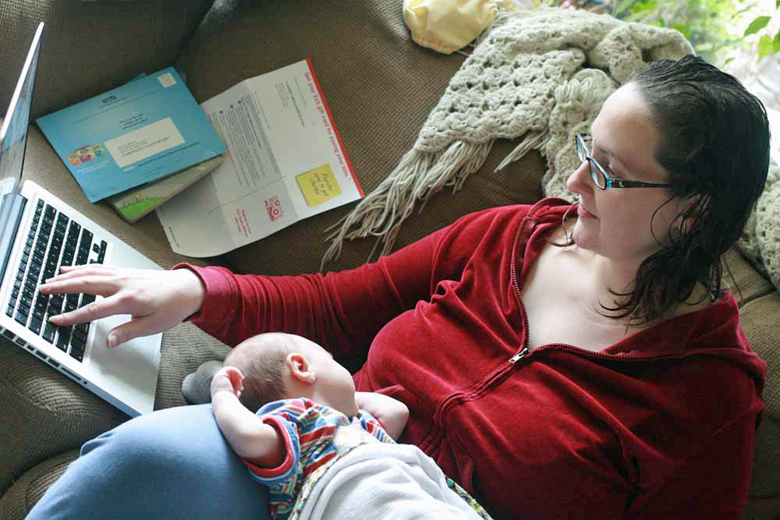 blogging mom with newborn baby alrik anb on lap typing on computer