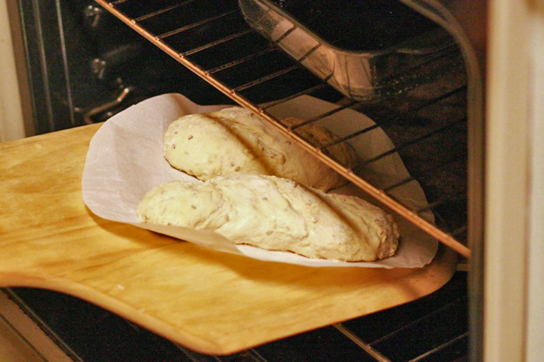 sliding loaves into oven onto pizza stone with pizza paddle - cooking homemade easy bread recipe