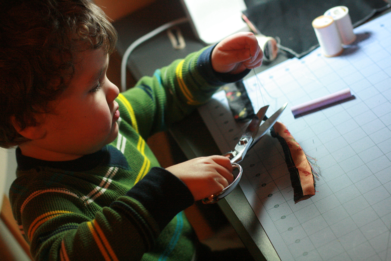 boy helping sew a mei tai carrier for babywearing