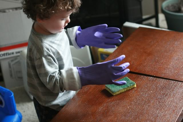 toddler cleaning wearing big dish gloves